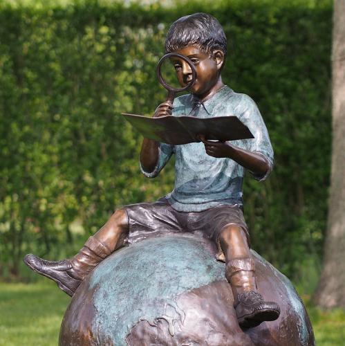 Bronzefigur Junge mit Lupe auf Weltkugel