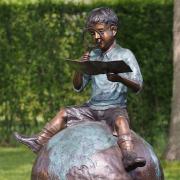 Bronzefigur Junge mit Lupe auf Weltkugel